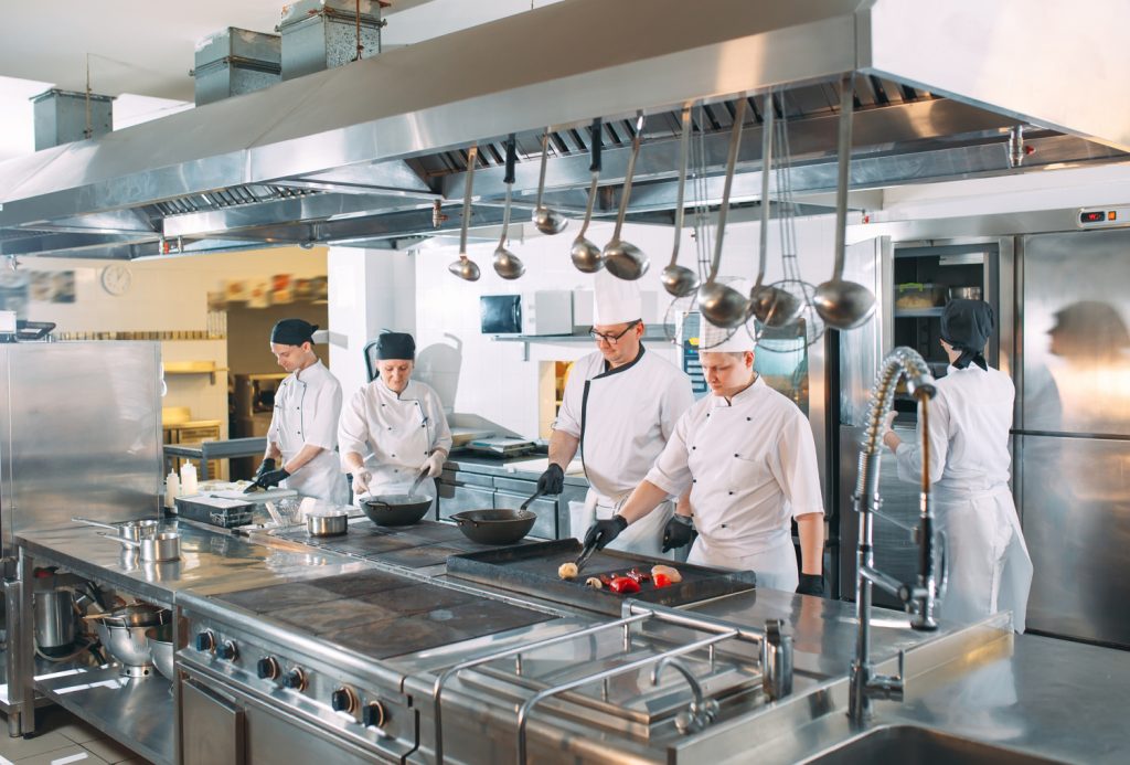 chefs working in a busy commercial kitchen with stainless steel appliances