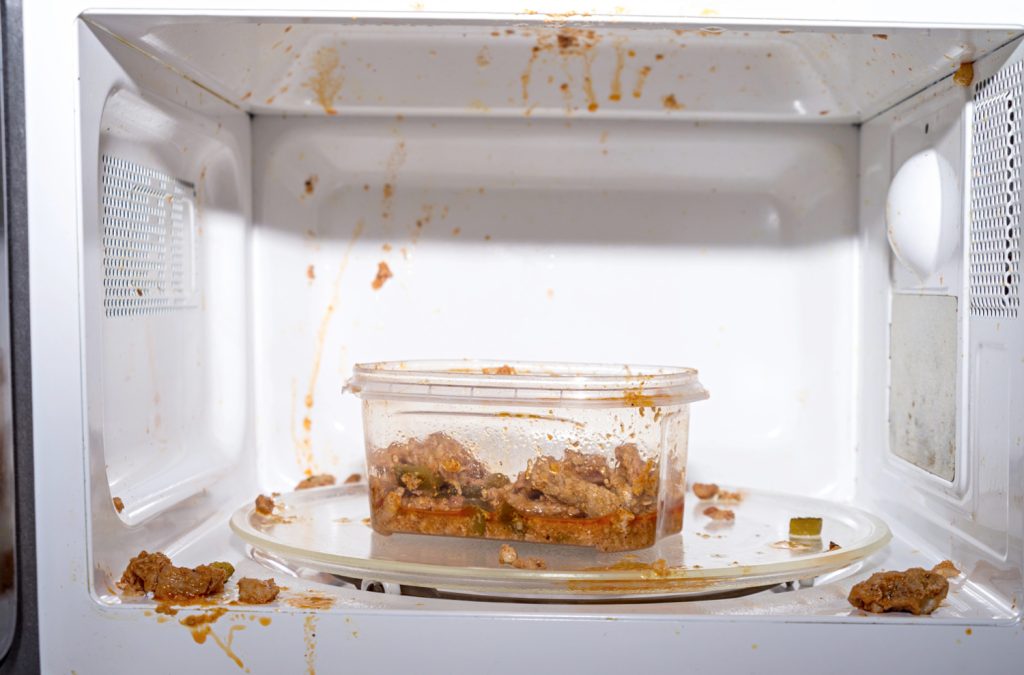 dirty microwave with a bowl of pasta inside