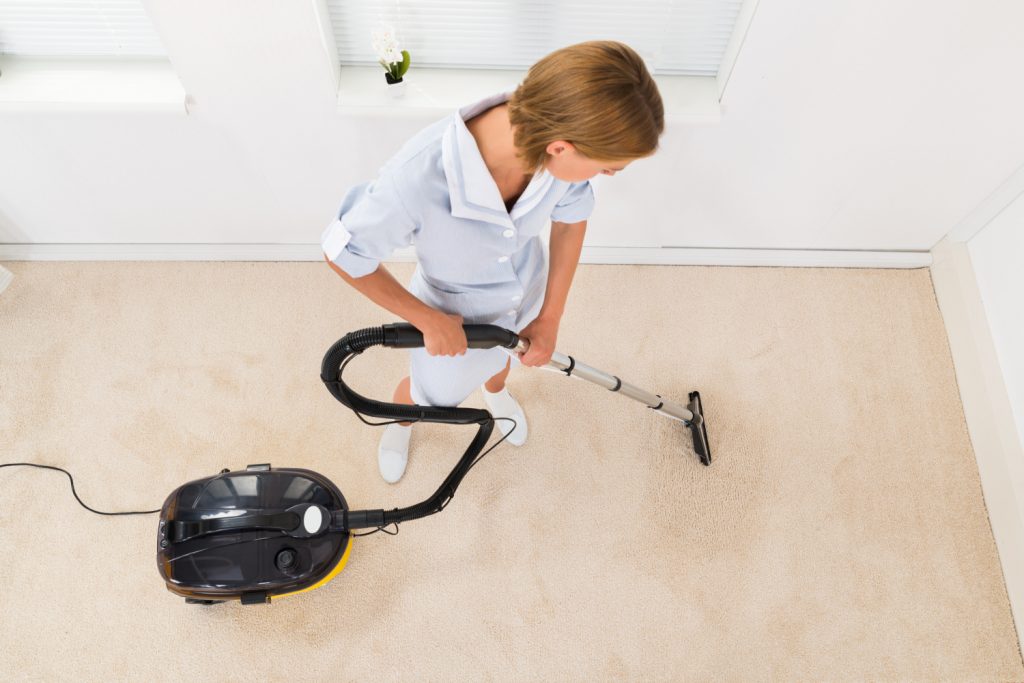 A woman vacuuming a carpet in a closet