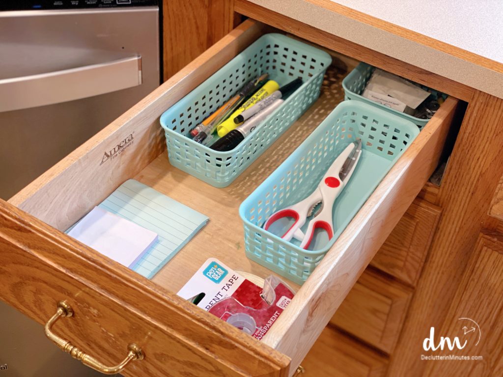 an organized junk drawer in a kitchen with containers fills with office items