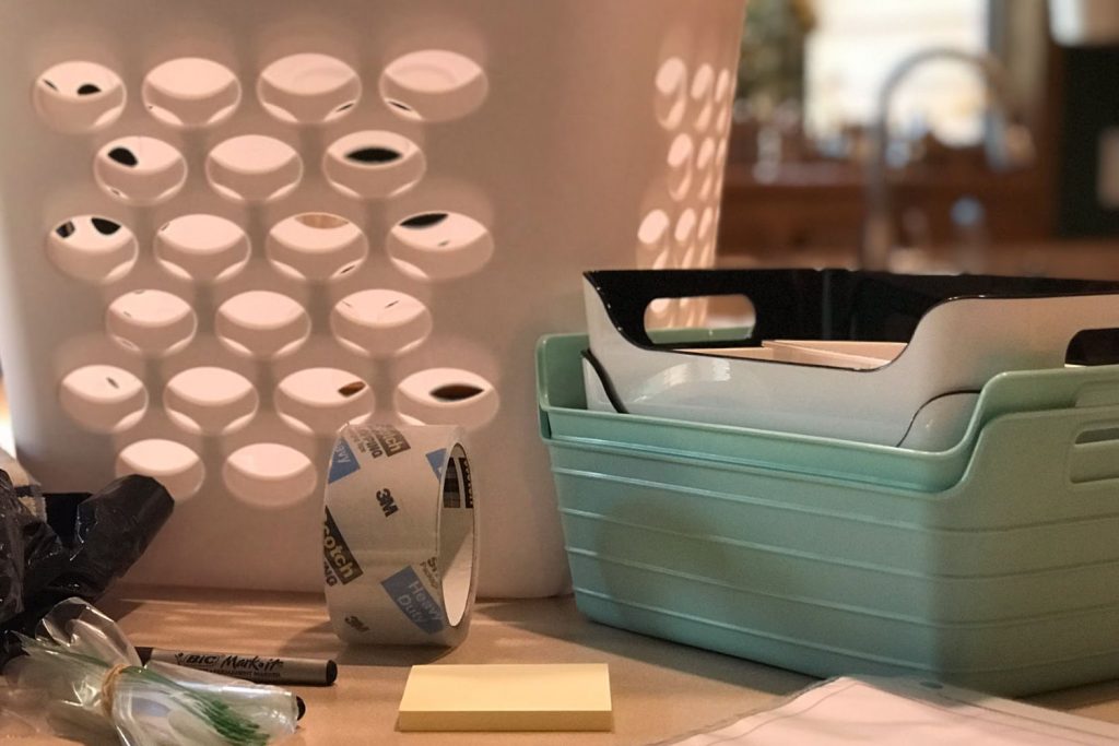 Tan kitchen counter with laundry baskets and a stack of teal, black, and white organizing bins.