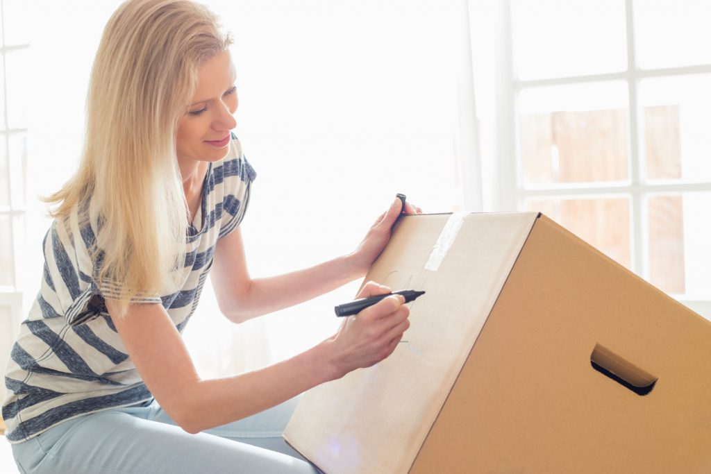 woman labeling a box. Easy decluttering tips you can do to test drive decluttering.