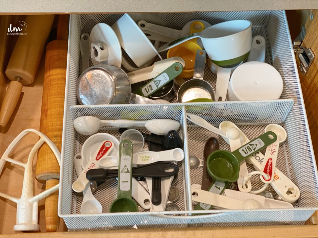 A drawer organizer filled with measuring cups, spoons, and various kitchen tools, neatly sorted into compartments