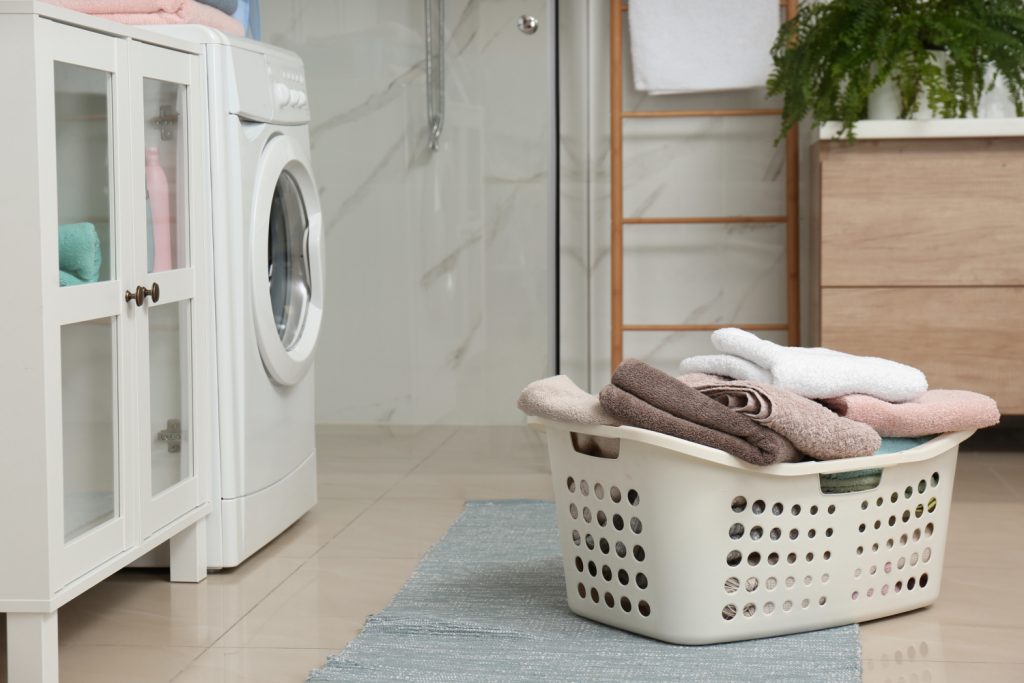 Basket with laundry and washing machine in bathroom