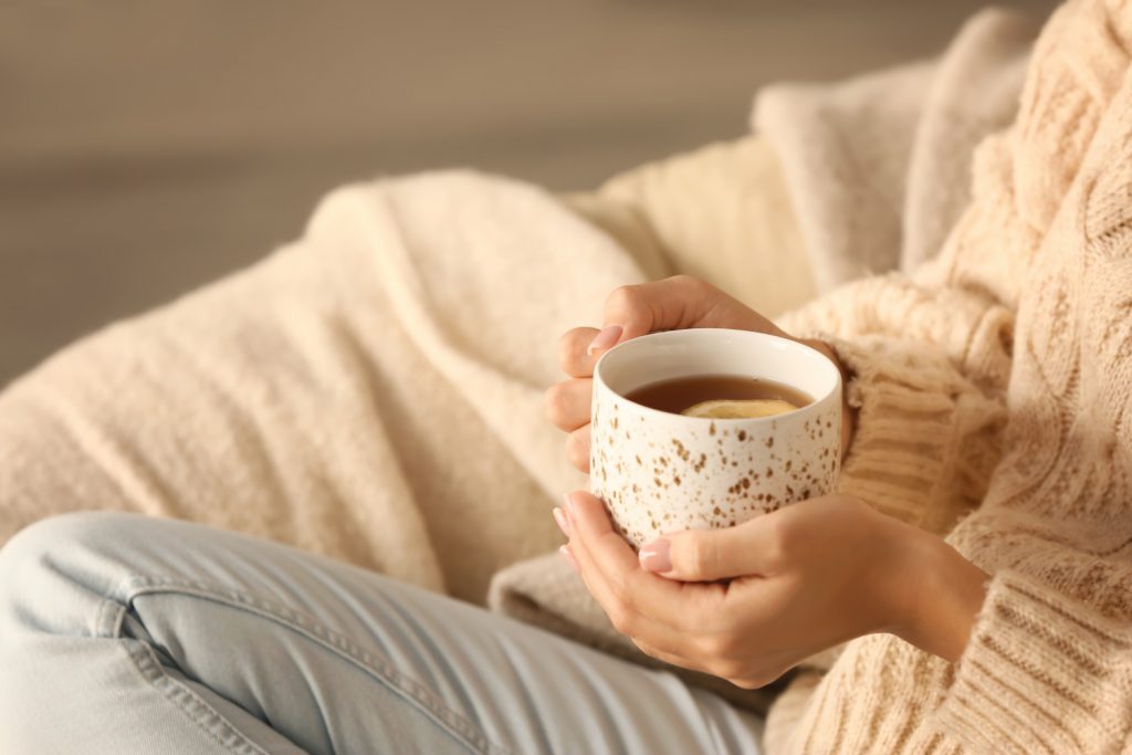 Young woman drinking hot tea at home, closeup