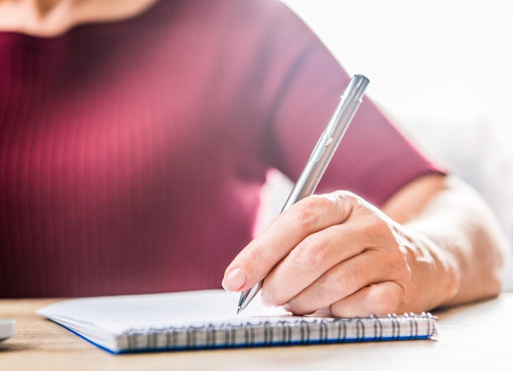 a woman in red making a list on a pad of paper