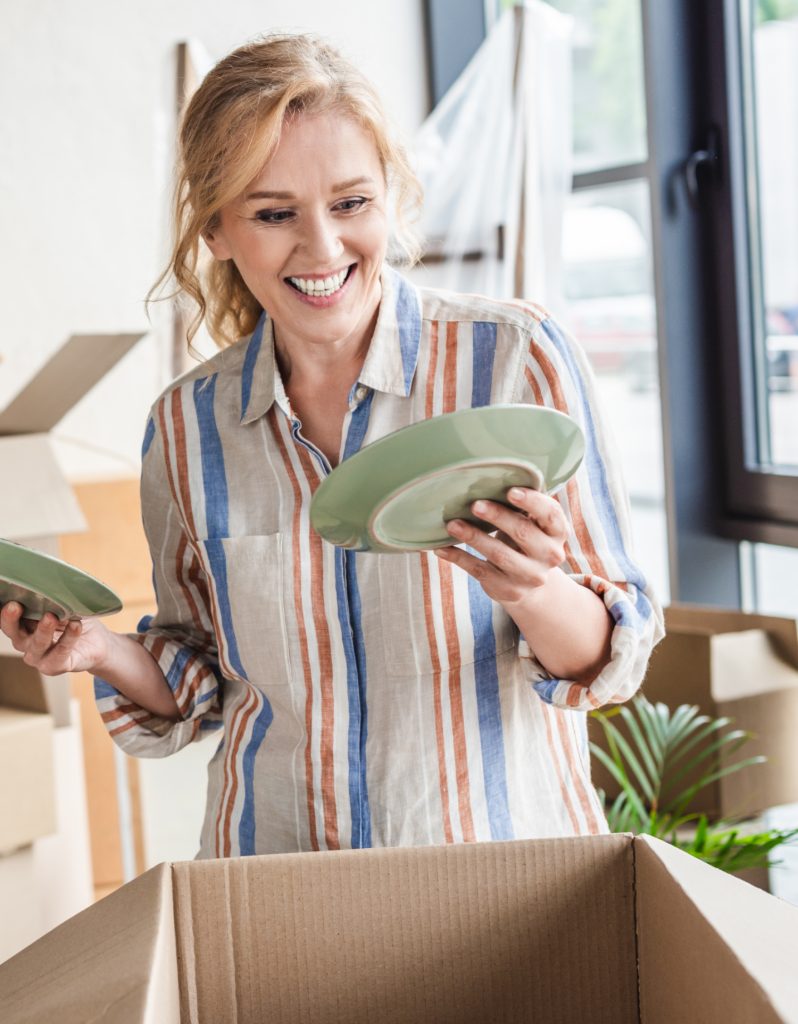 a woman putting green dishes into a box for donations