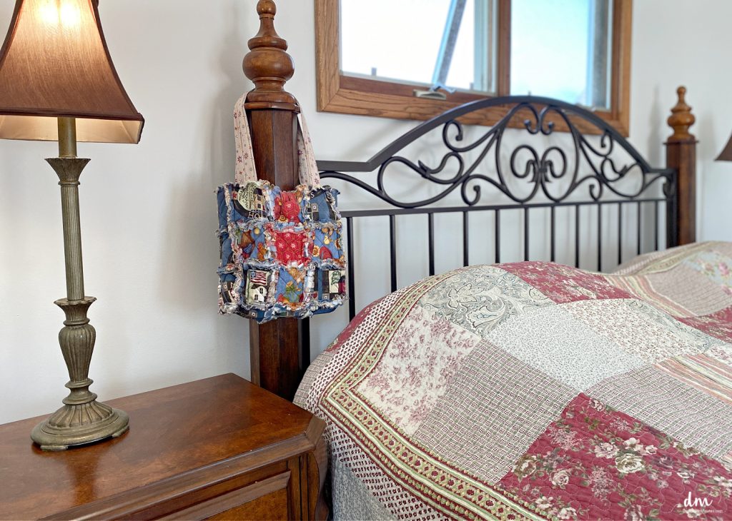 a bag hanging on the side of a headboard in a bedroom