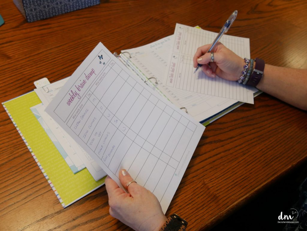 a set of hands holding papers writing a decluttering list for a home