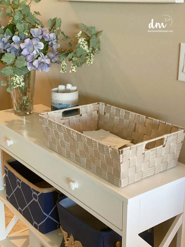 a tan basket filled with clutter sitting on a white table in a home