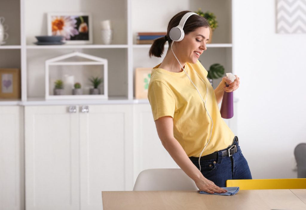 a woman with white headphones cleaning a table 