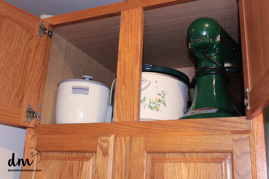 crock pot, mixer, and rice cooker in an upper cabinet of a kitchen