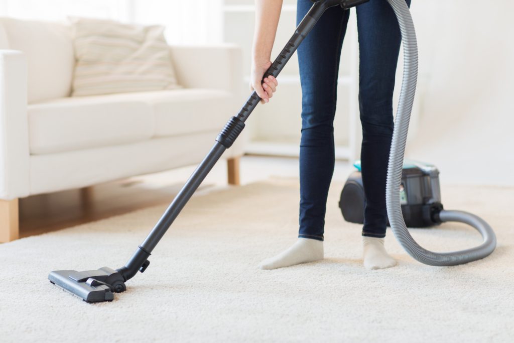 woman vacuuming a carpet in a family room