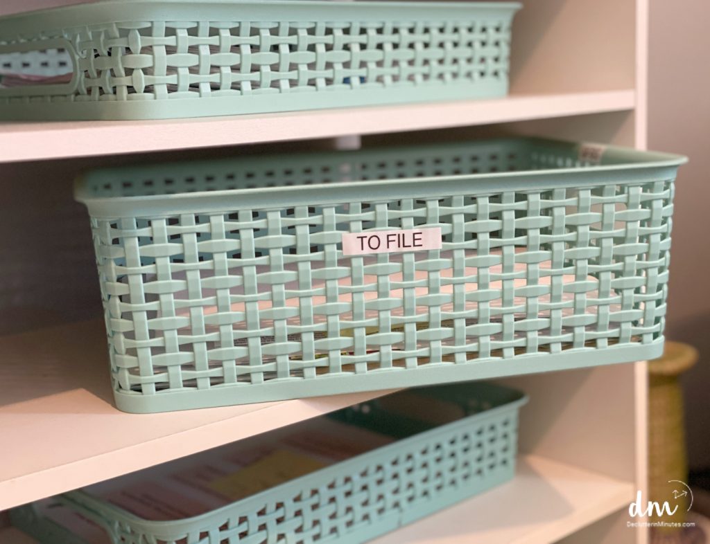 A LIGHT TEAL BASKET LABELED TO FILE ON A WHITE SHELF