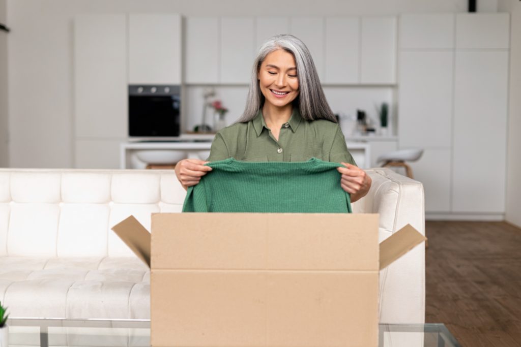 a woman putting a green shirt into a donation box