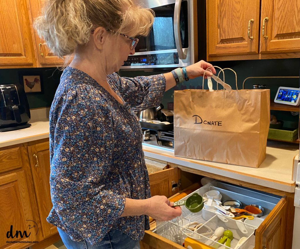 a woman putting measuring spoons into a donation back in a kitchen