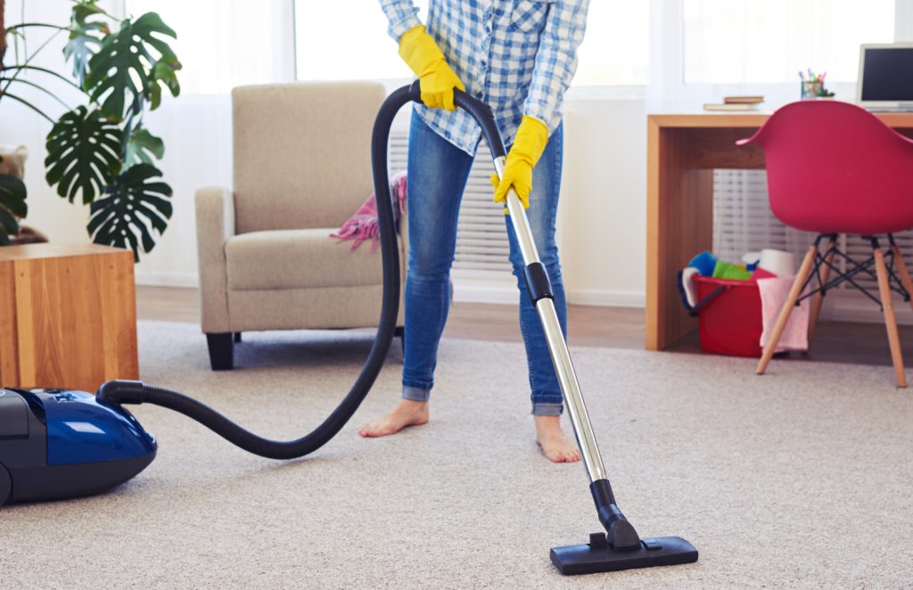 a woman in bare feet vacuuming a room