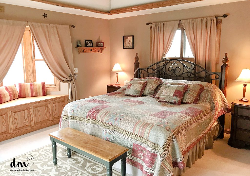 a bed in a room with a window seat, bench, and nightstands
