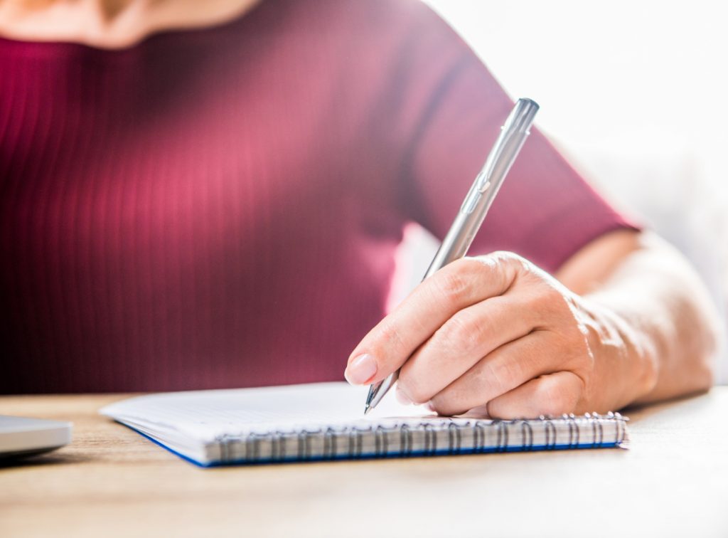 a woman making a list on a pad of paper