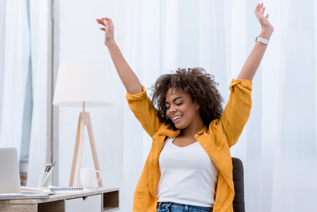 woman happy arms up at a desk