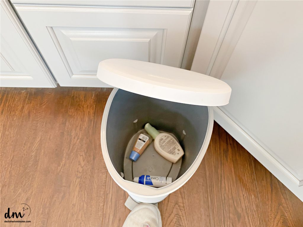 a white trash can with expired makeup inside 