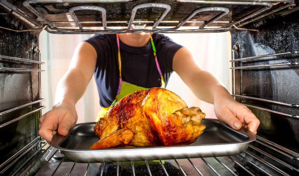 Housewife prepares roast chicken in the oven, view from the inside of the oven. Cooking in the oven.