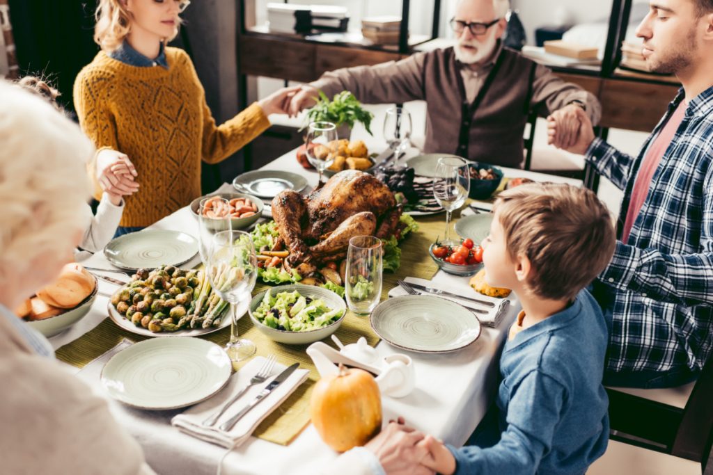 family holding hands before enjoying thanksgiving dinner