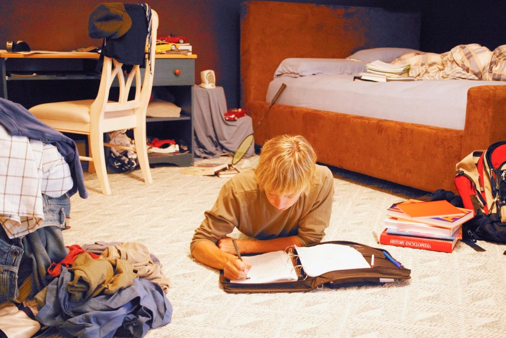 a boy lying on his stomach doing homework.