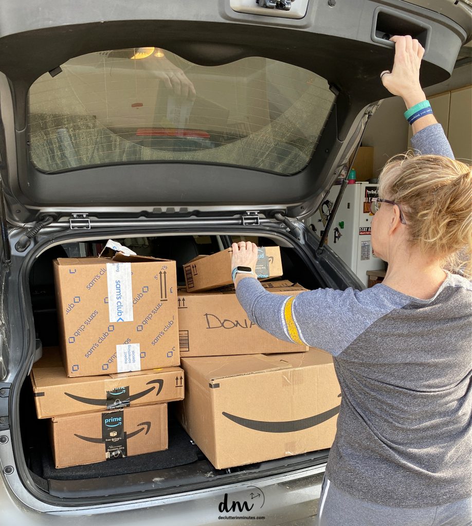 a woman putting donation boxes in the back of her car.