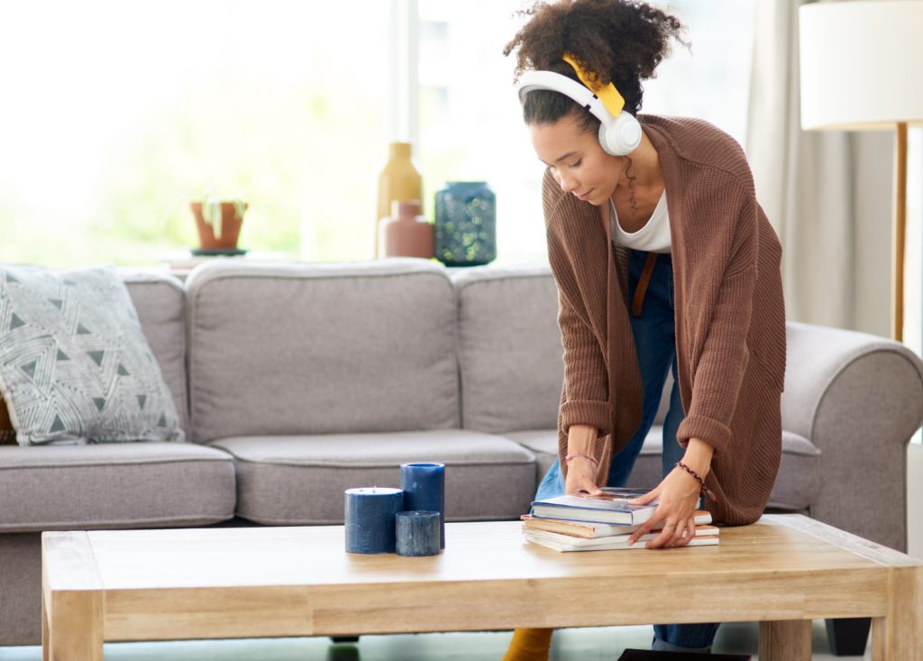 woman decluttering a coffee table wearing headphones