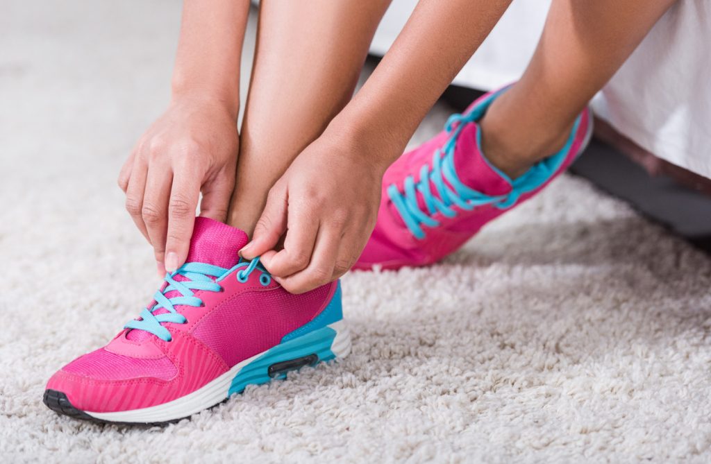 woman tying her pink sneakers in a family room