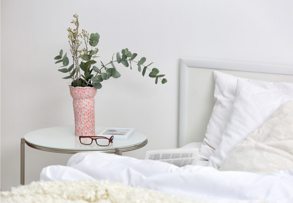 Bedroom interior with bed and flowers on nightstand