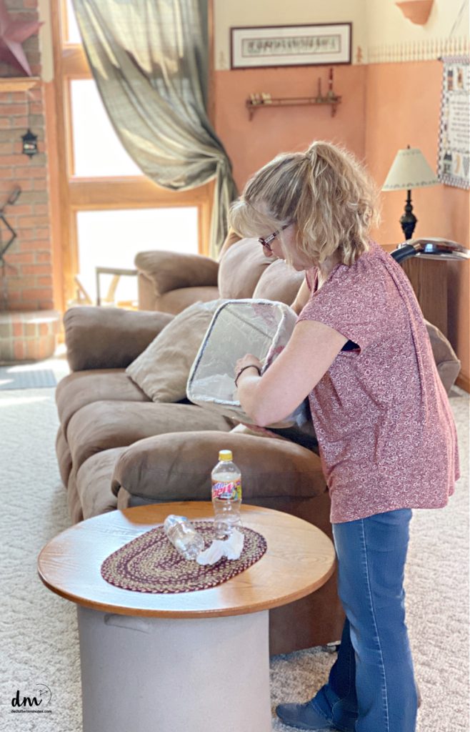 a woman in red picking up trash in a family room