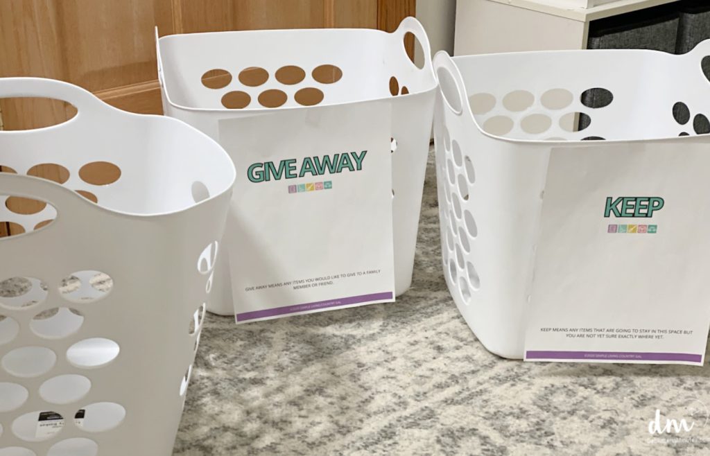 three white laundry baskets with labels on them for sorting clutter