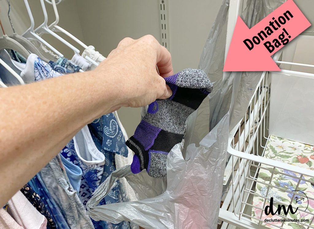 a hand putting socks into a plastic bag in a closet