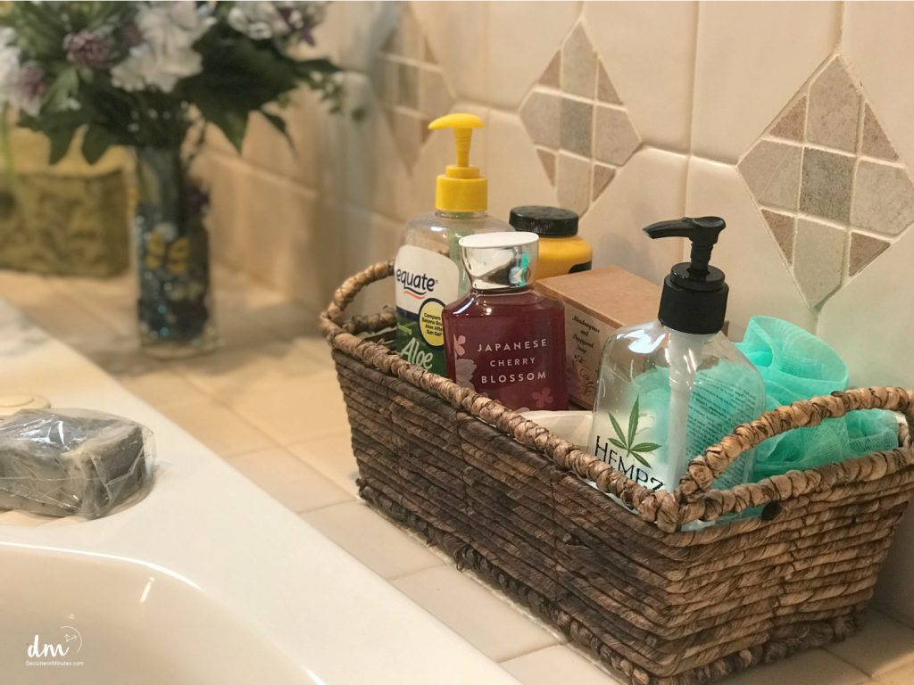 A basket of bath supplies sitting on the edge of a tub
