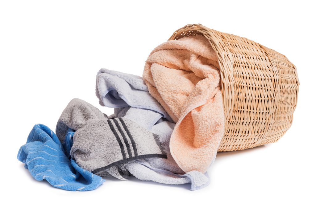 a basket on it's side with bath towels falling out