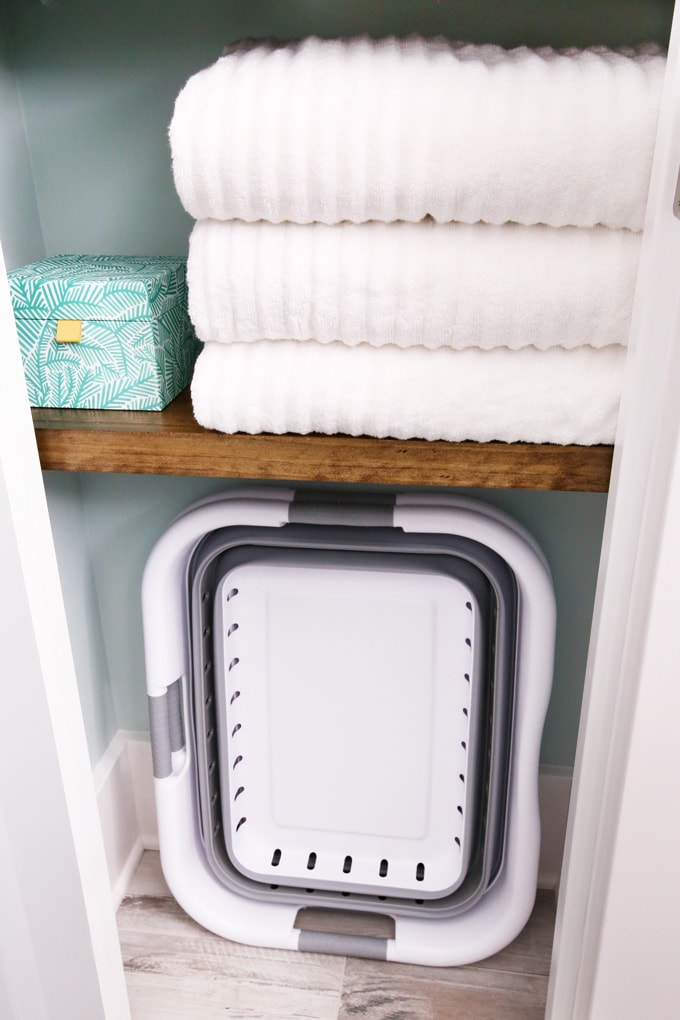 towels folded on a shelf. laundry basket on the bottom