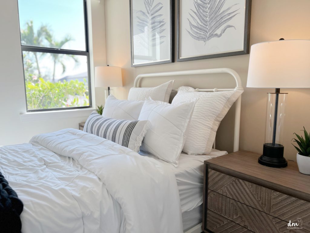 a white bed with a lamp on a nightstand