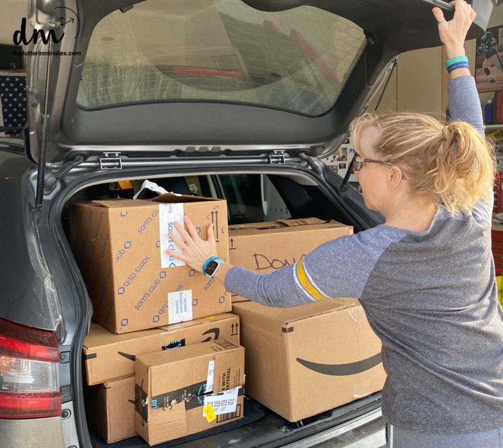woman putting donation boxes into the back of a car