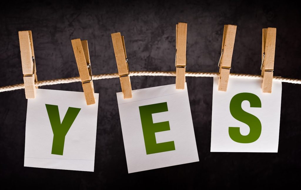 Letters spelling 'YES' clipped to a rope with wooden clothespins 