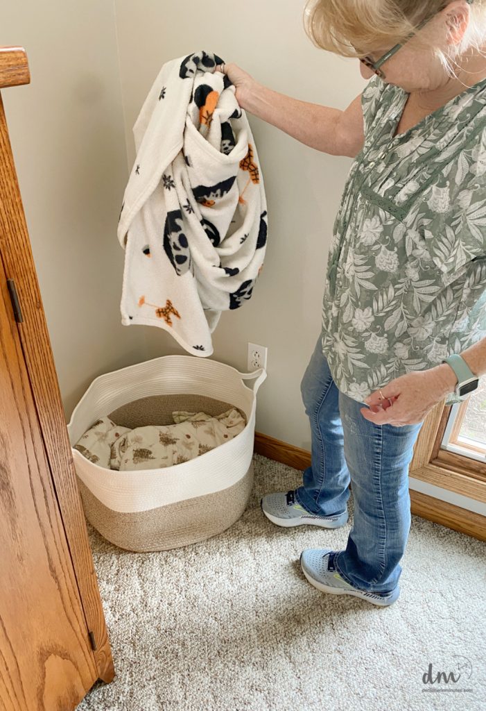 a woman putting a blanket into a large basket 