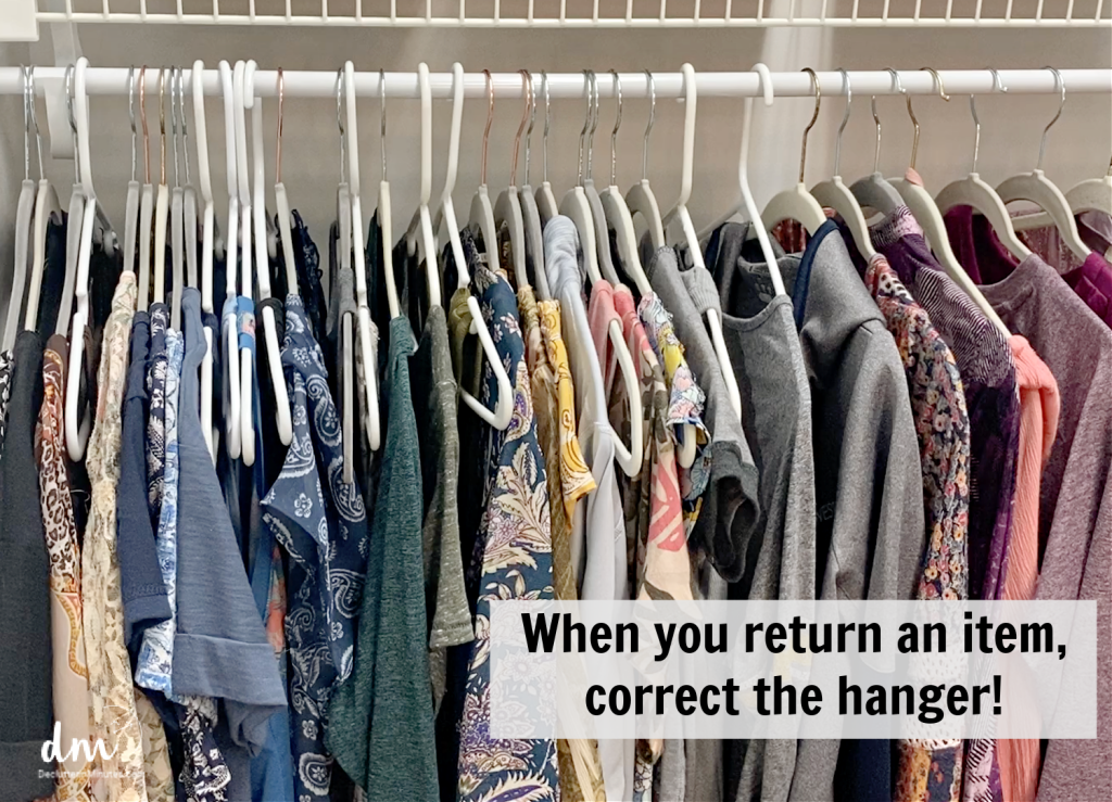 A closet with various clothes on mismatched hangers, featuring a reminder to correct the hanger when returning an item
