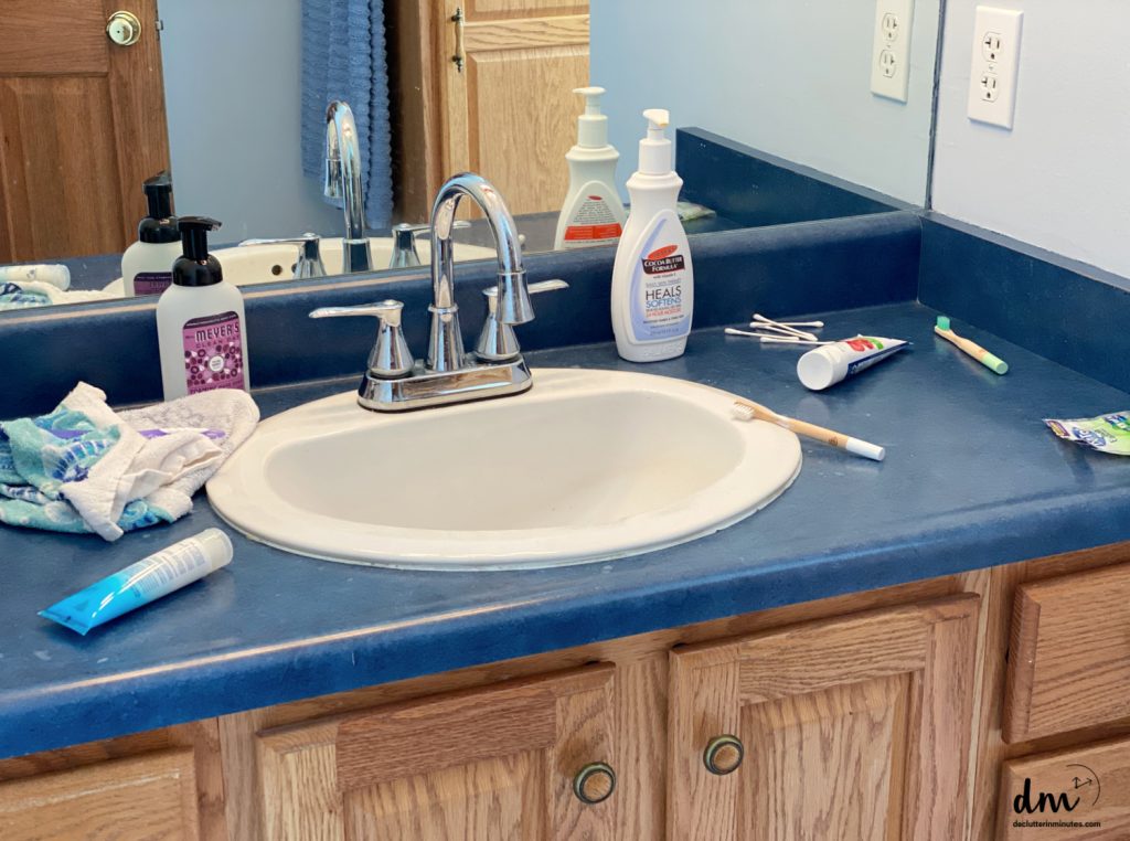 a cluttered sink and counter area in a bathroom