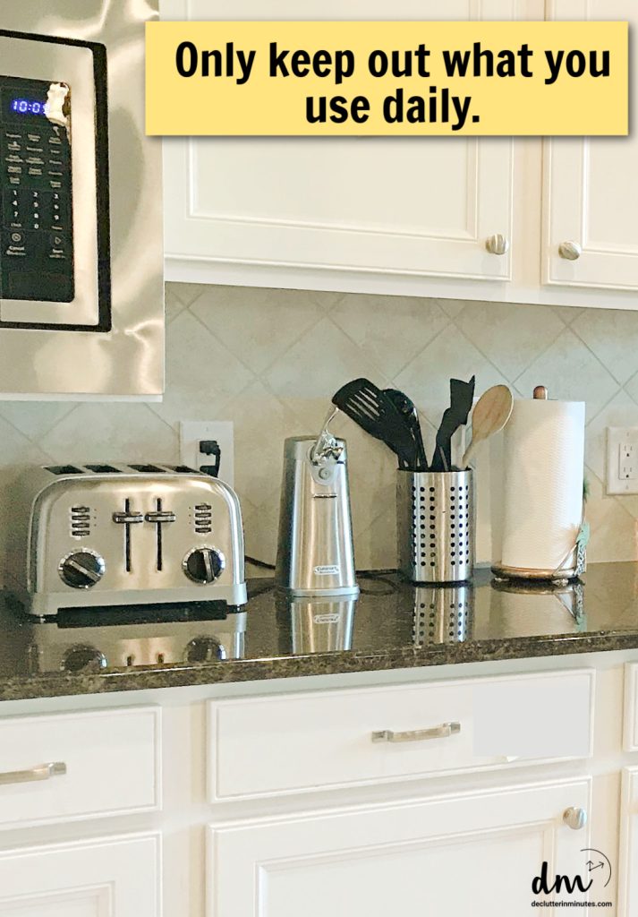 a counter in a kitchen lined with small gadgets-words "only keep out what you use daily" on a yellow box