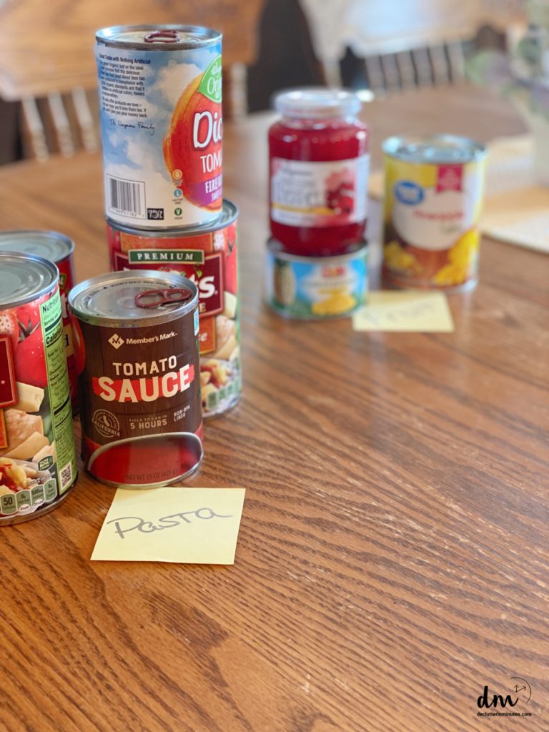 a sticky note labeled, pasta in front of a stack of sauce cans
