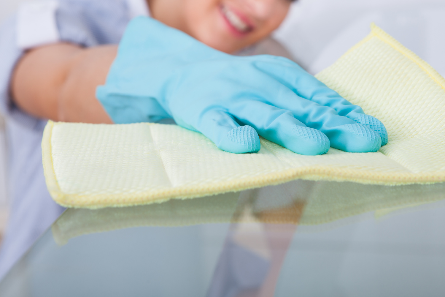 a woman cleaning a counter with a glove and rag