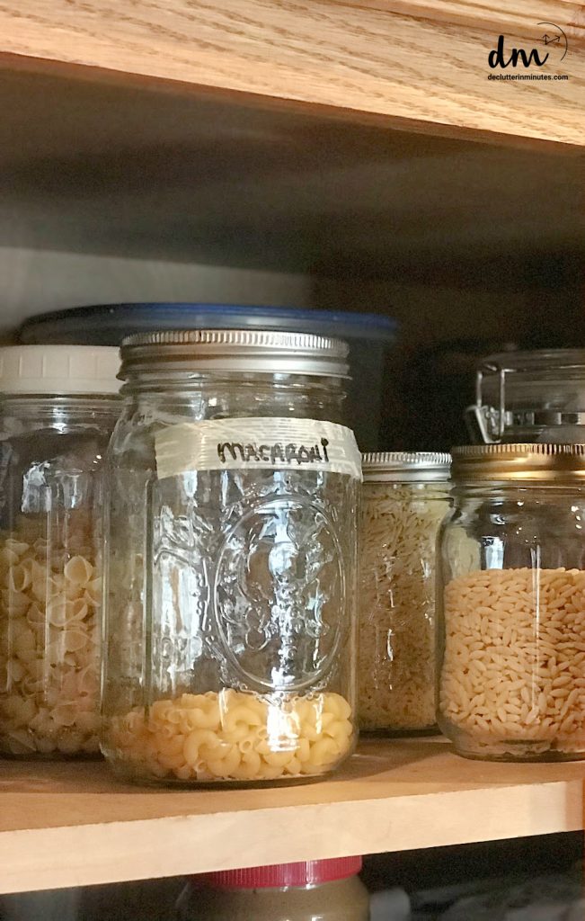 mason jars on a shelf in a kitchen without a pantry that are filled with dry goods and labeled.
