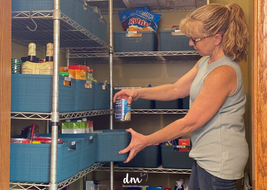 woman putting cans in a basket in a pantry