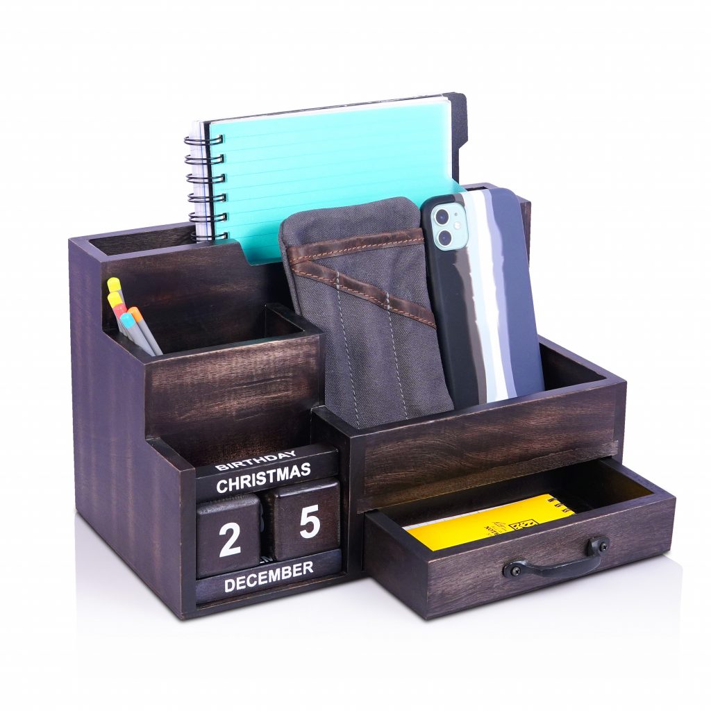 Image that shows: A wooden organizer that hold pencils, mobile phone, and a notebook. It also has a small drawer and a calendar blocks.